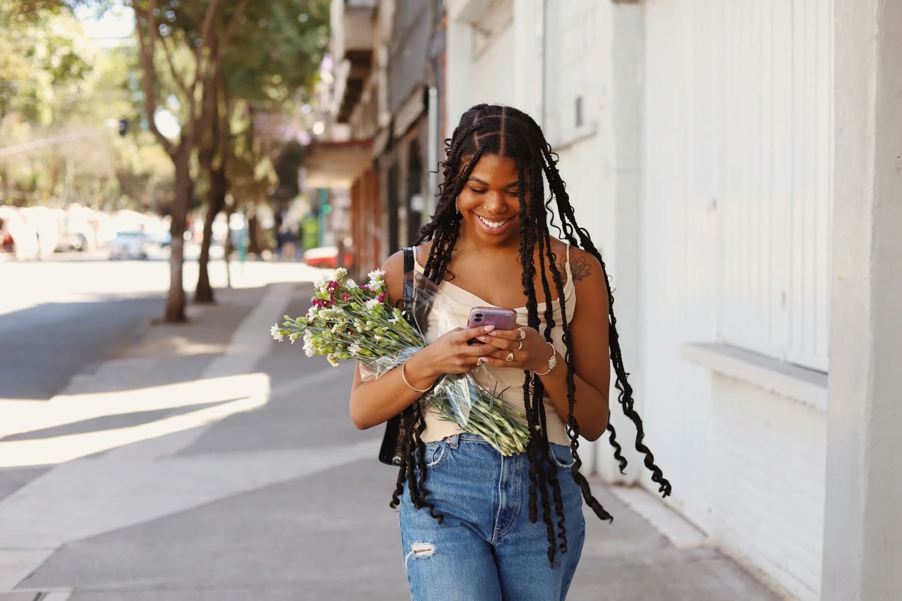 A young woman smiling at her phone as she walks down a city street