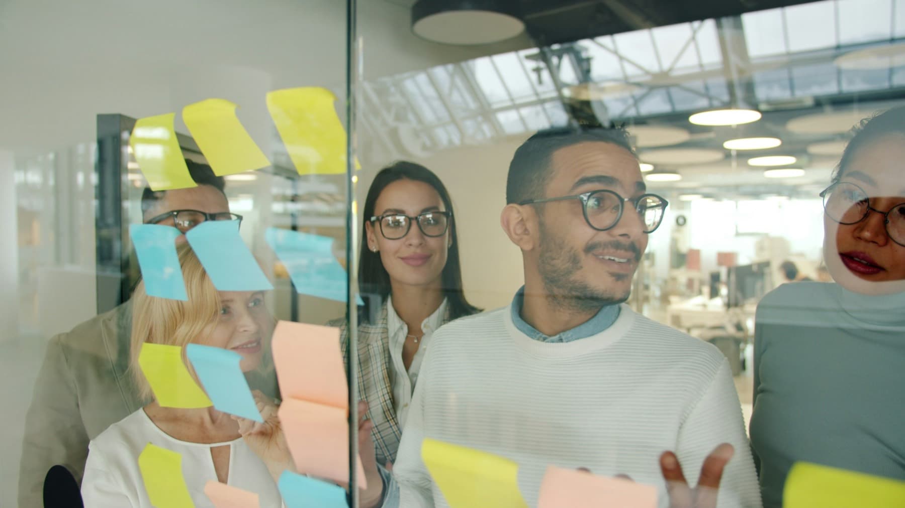 A team planning a project together on a glass wall of sticky notes